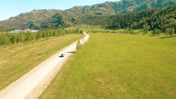 飞过群山和草地上蜿蜒的道路上的汽车农村公路下面