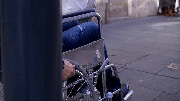 一个年轻的残疾人推着轮椅在拥挤的人行道上行走