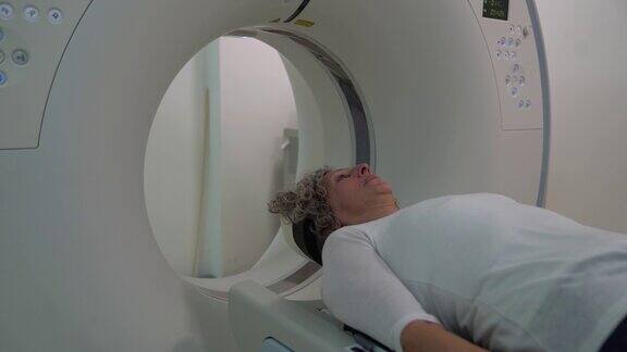 女老年病人躺在医院准备进行MRI脑部扫描