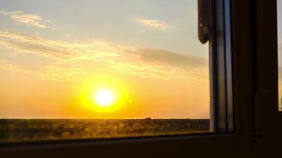 透过窗户看日落明亮的黄色太阳移过地平线时间流逝