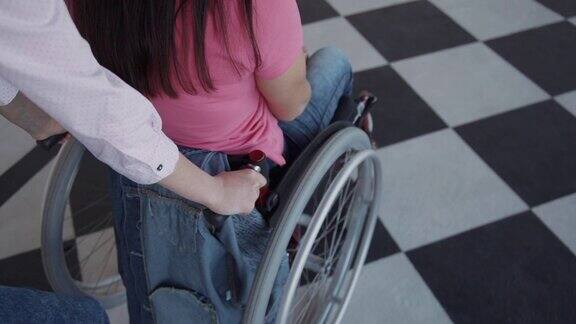女助手骑在轮椅上的残疾妇女坐在医院内部