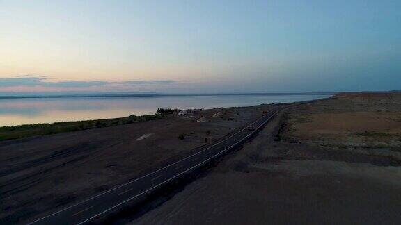 日落时分汽车在沙漠中间的空旷道路上行驶的鸟瞰图