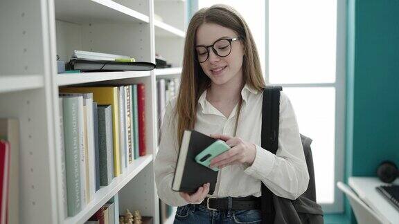 年轻的金发女学生在大学教室里用智能手机找书