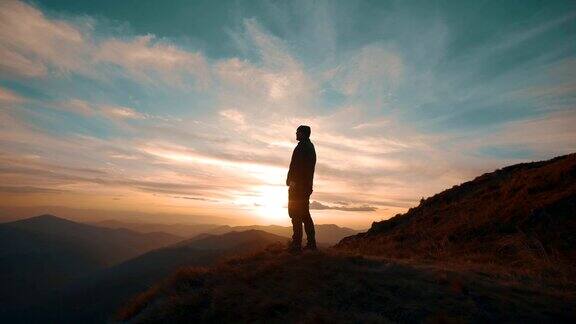 一个人站在山上映衬着美丽的夕阳