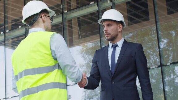 戴安全帽的商人和工程师在建筑工地握手