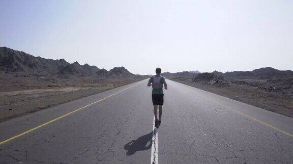 男性跑步者沿着铺设的沙漠道路慢跑