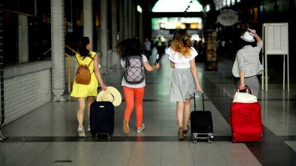 四个穿着鲜艳夏装的女性朋友赶不上飞机了漂亮的女孩在机场里跑步手里拿着文件、机票和大行李箱