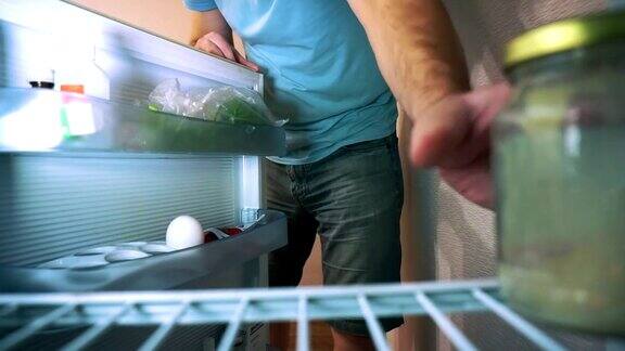 男人打开冰箱他的一半是空的露出他的脸把罐子放进冰箱