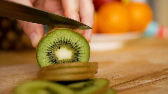 男子用刀在木板上切猕猴桃背景是水果和蔬菜特写镜头