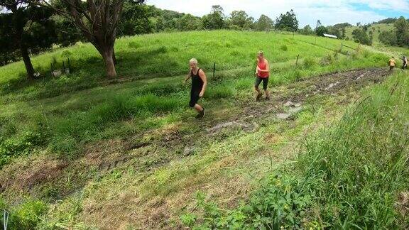 一群中年妇女在一个泥泞的泥潭中跑在越野障碍赛跑