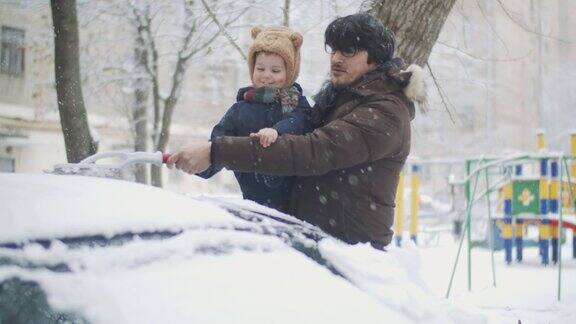 一家人在冬天清除汽车上的雪
