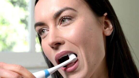 在浴室用电动牙刷刷牙的女人