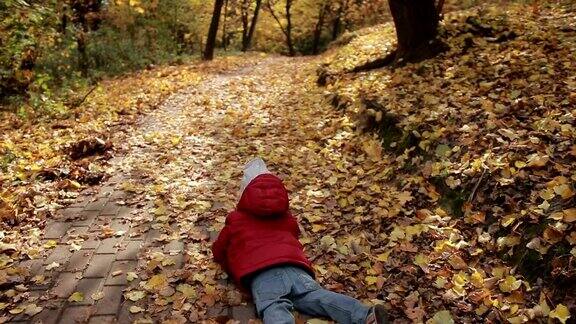 蹒跚学步的小男孩在五彩缤纷的秋天公园里奔跑