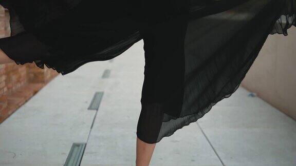 年轻的职业芭蕾舞演员穿着黑色的裙子在户外跳舞