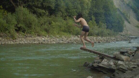 兴高采烈的男子从木制跳板上跳入山河