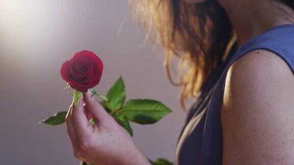 手持一朵红玫瑰的年轻女子
