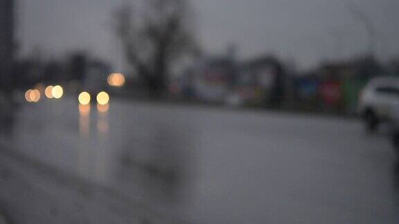 黄昏的黑暗中汽车在潮湿的道路上行驶
