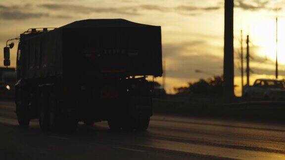 剪影日落时桥上卡车和拖车的交通