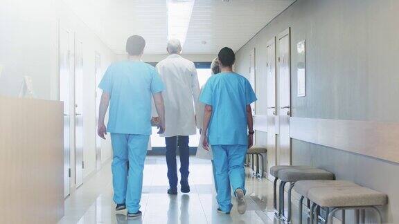后视图的医生护士和助理走过医院的走廊专业医务人员工作拯救生命缓慢的运动