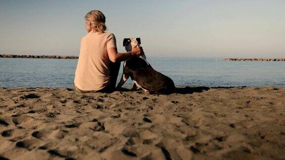 成熟的女人在沙滩上放松和宠物狗