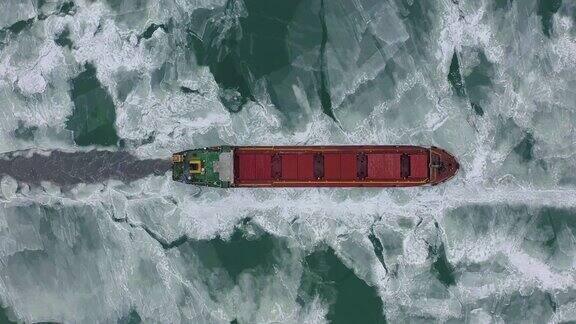 在极端冬季条件下在冰冻海面上航行的货船航拍在破冰船造成的狭窄航道中航行北方寒冷冬季的水运