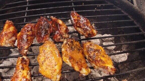将香料洒在户外烧烤架上点燃的木炭团上的金属格栅上腌制过的鸡翅上