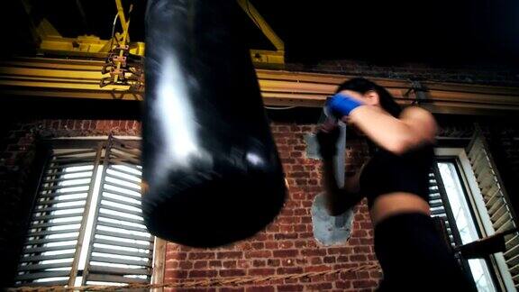 职业综合格斗选手苗条的女孩与完美的身体锻炼在阁楼拳击工作室背景