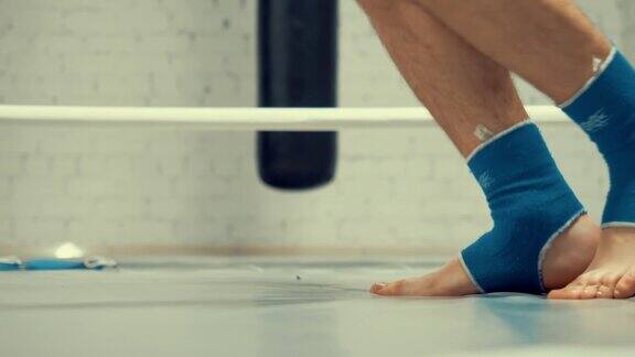 在搏击俱乐部进行有氧训练时拳击手双腿在跳绳上跳跃自由搏击训练用跳绳跳远热身运动