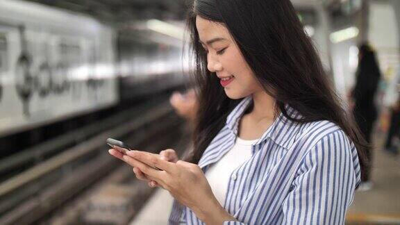 亚洲女子在等火车时用智能手机搜索