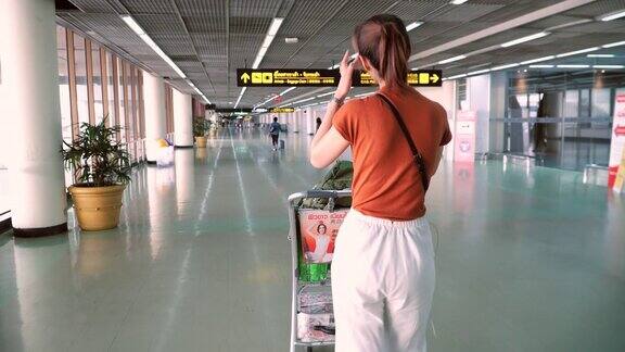带着行李走过机场候机楼的女性游客