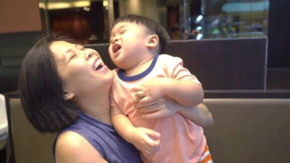 快乐的亚洲母亲享受与她的儿子在餐厅午餐