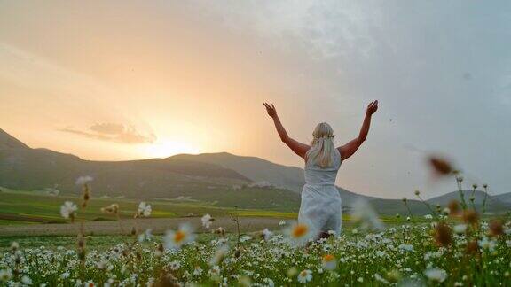 无忧无虑的年轻女子奔跑在田园诗般的草地在日出卡斯特鲁西奥翁布里亚意大利