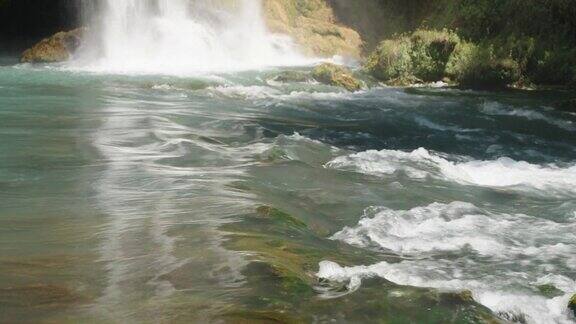 水很快从岩石上流下来山区河流瀑布打在岩石上绿松石的颜色