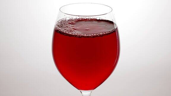 红酒从瓶中倒入高脚杯背景为白色玫瑰酒倒入杯中葡萄酒杯