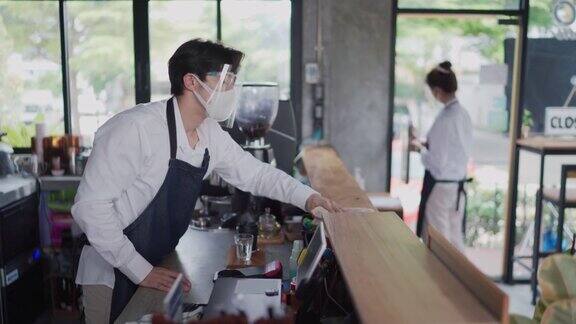 年轻的亚洲夫妇打扫他们的咖啡馆准备重新开张的小生意