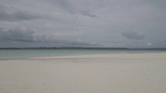 美丽的晴天在一个平静的原始海滩与灰色的天空在印度尼西亚