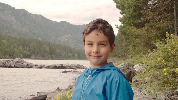 夏日里微笑的男孩站在山间河边