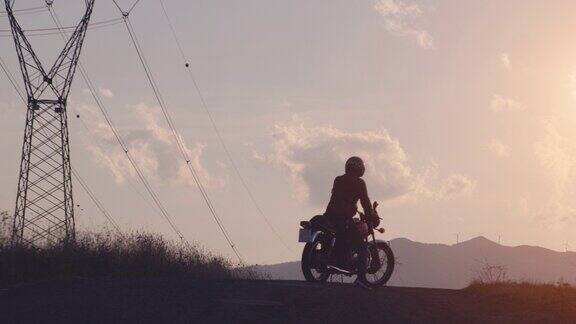 夕阳西下一名男子驾驶着一辆红色的摩托车到达意大利托斯卡纳乡村美丽的山景路上沃尔泰拉
