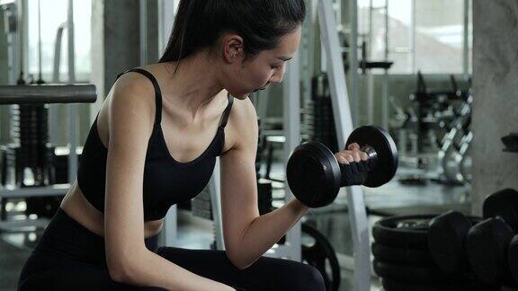 美丽的运动女人在健身房里用哑铃锻炼