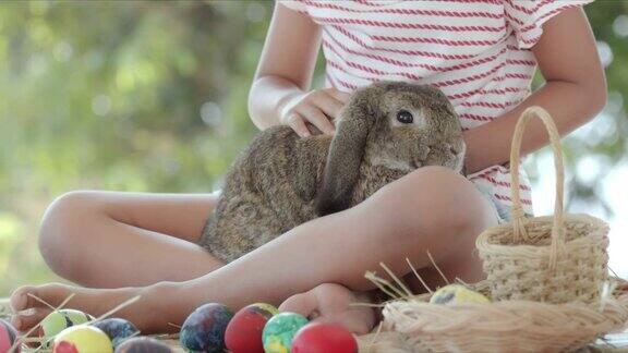 亚洲小女孩在复活节书桌上照顾她的膝盖上的兔子