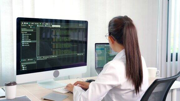 亚洲女性程序员打字源代码在电脑上编程在办公室自由网站开发概念