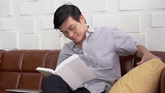 亚洲老人眼镜教授坐在椅子上读课本与copyspace