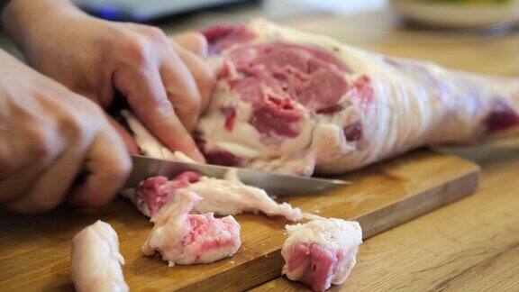 从一大块肉上整条羊腿上把肥肉切下来放在砧板上