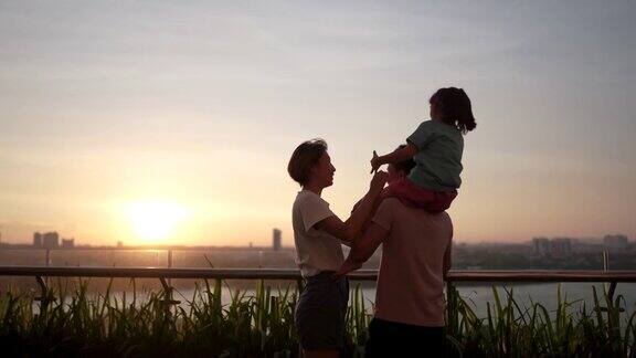一个亚洲华人家庭和一个孩子在户外欣赏春天的日落美景