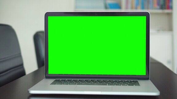 办公桌上绿色屏幕笔记本电脑屏幕的办公室照片