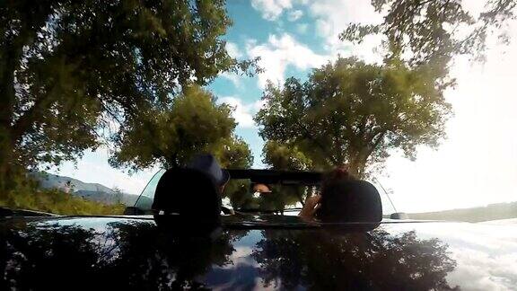 4K视频:敞篷汽车后部的画面:一对夫妇正在开车
