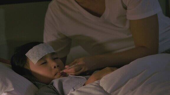 一位亚洲母亲晚上在床上照顾生病的女儿