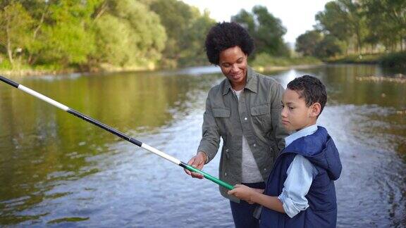慈爱的母亲和儿子在河边钓鱼