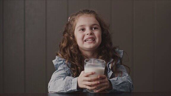 大头照欢快的小女孩拿着杯子喝着牛奶