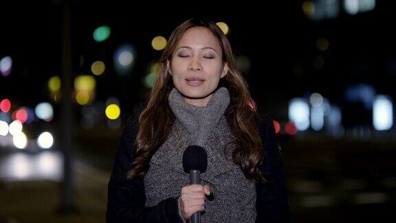 亚洲女新闻记者在市中心进行现场报道